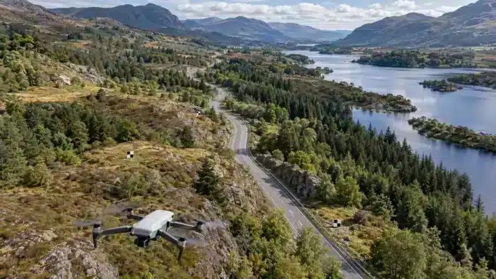 Drone surveying a winding road corridor with ground targets placed along the surrounding terrain